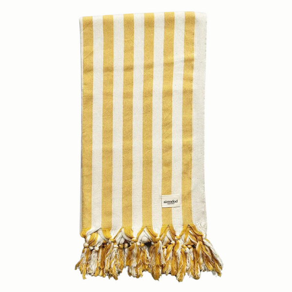 A cotton beach towel with large yellow stripes and a tassel fringe.