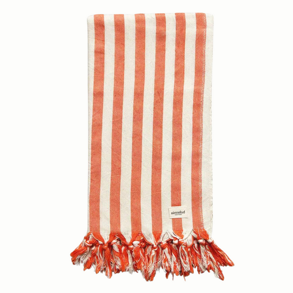 A cotton beach towel with large orange stripes and a tassel fringe.