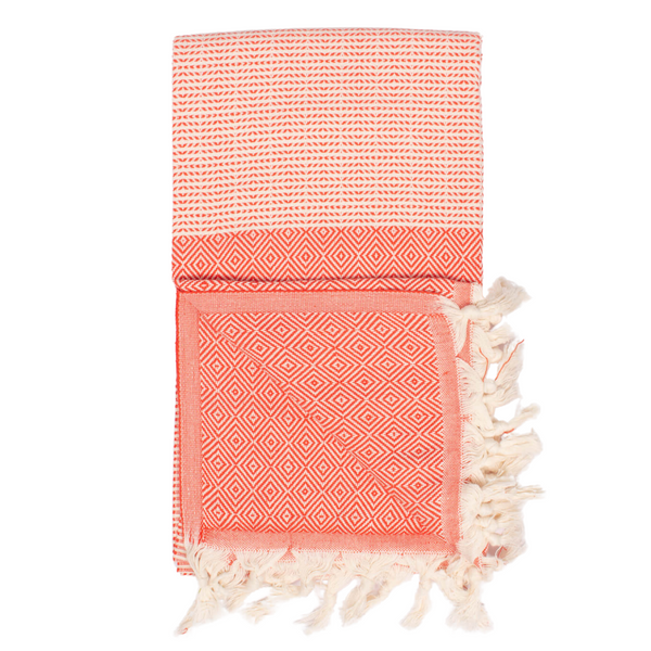 A cotton towel in a tangerine color with an intricate design and white fringe.